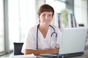 Closeup of beautiful nurse in front of laptop computer